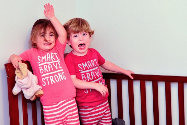 toddler boy and girl in matching pajamas that say "smart, brave, strong"